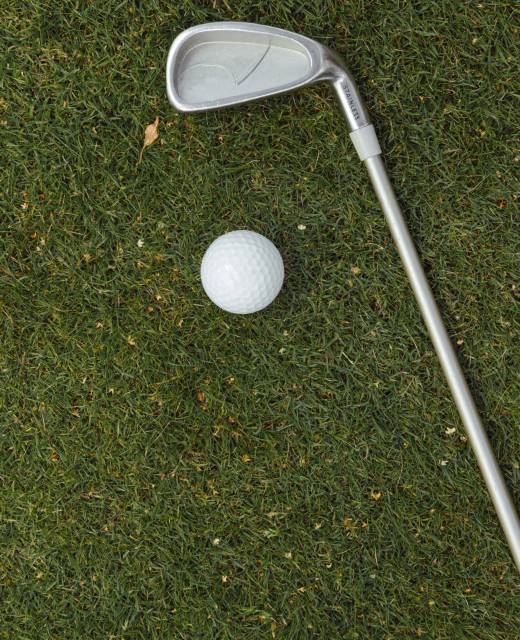 Golf ball and golf club on green grass on golf course, flat lay, top view